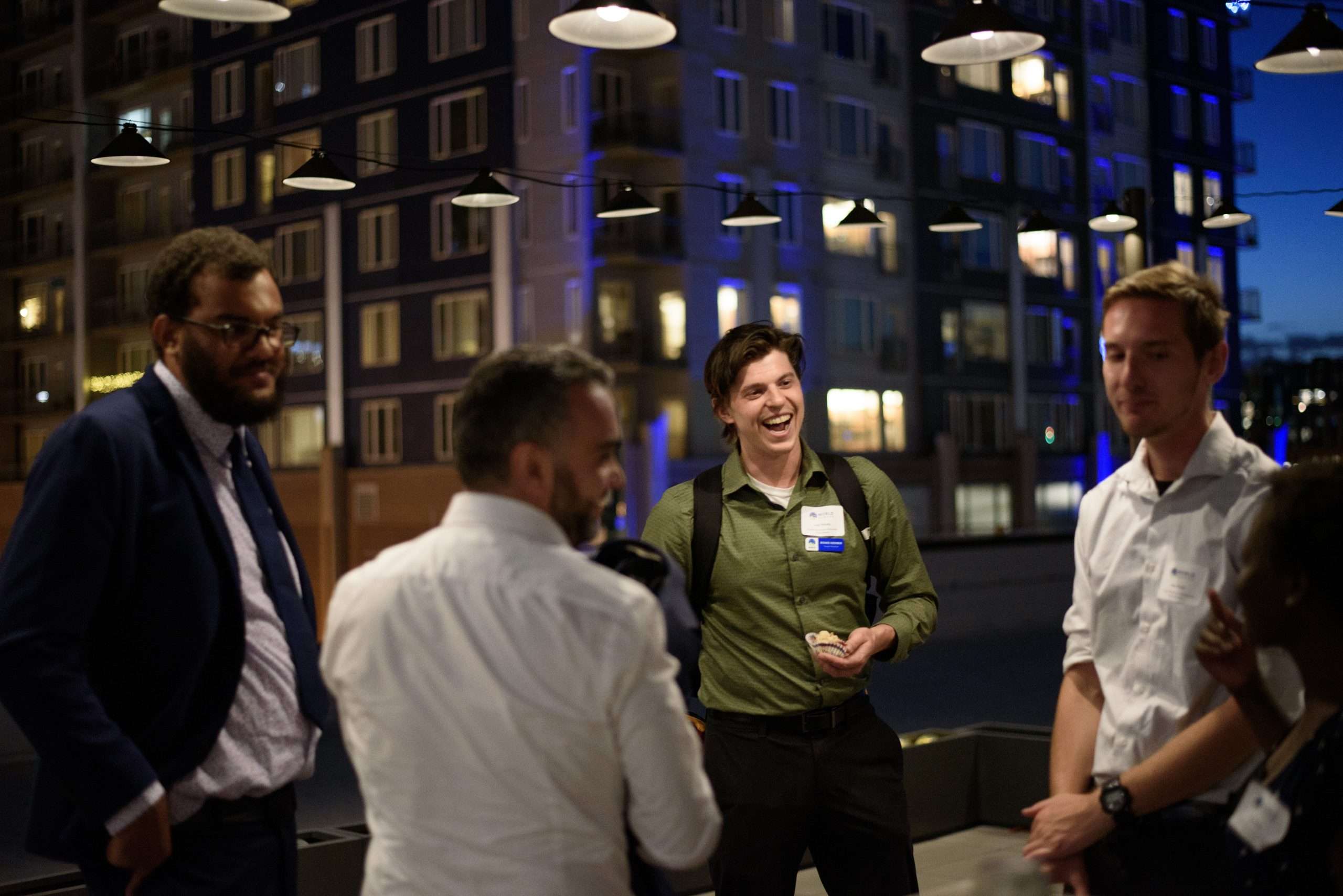A group of 4 people stand talking and laughing